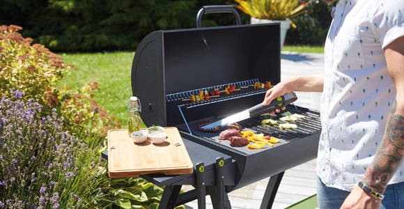 Homme qui cuit de la viande sur son barbecue au charbon